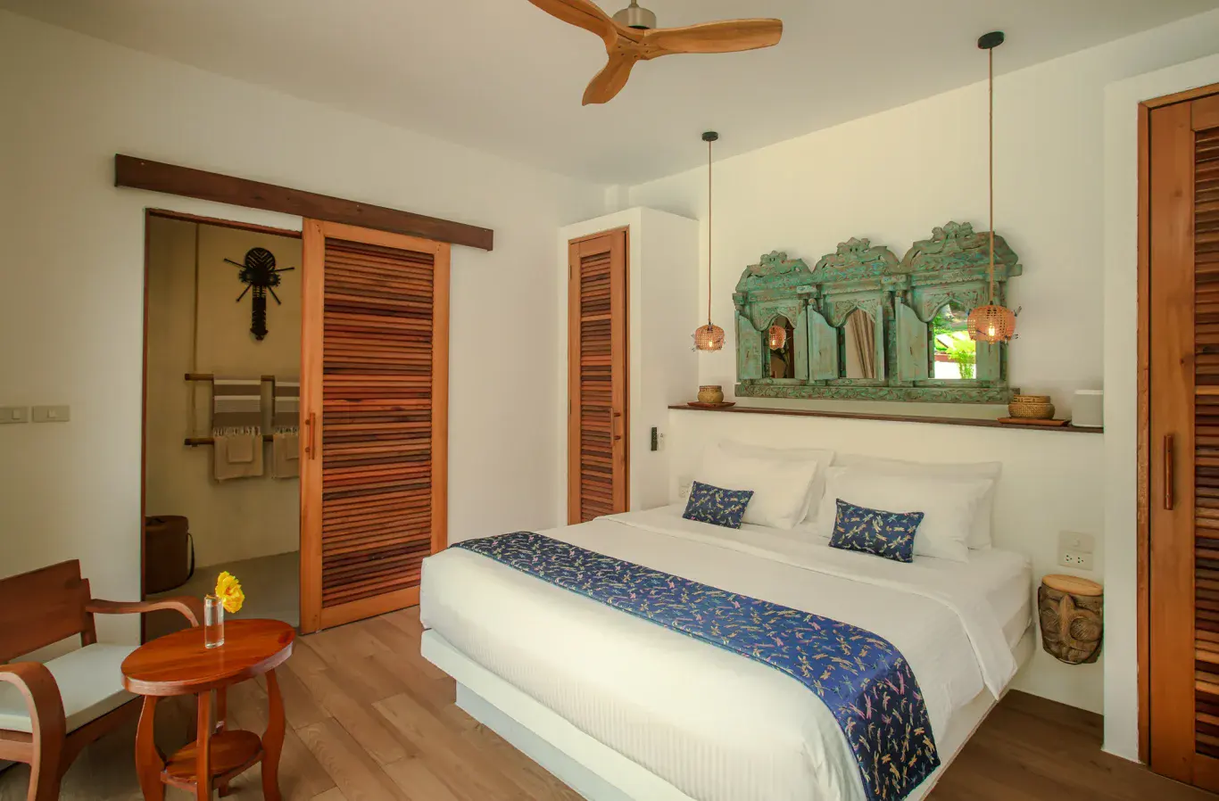 Het bed in de houten villa op Koh Phangan — warm licht, hout en linnen